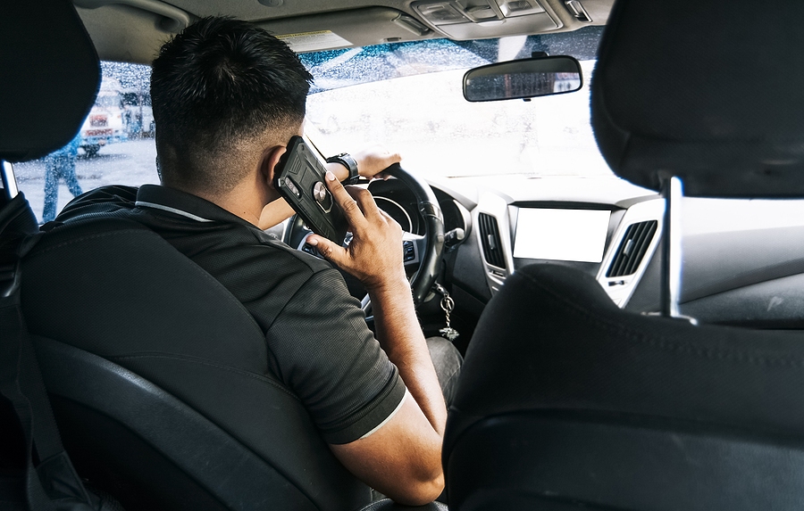Driver talking on phone while driving, illustrating distracted driving and road safety risk