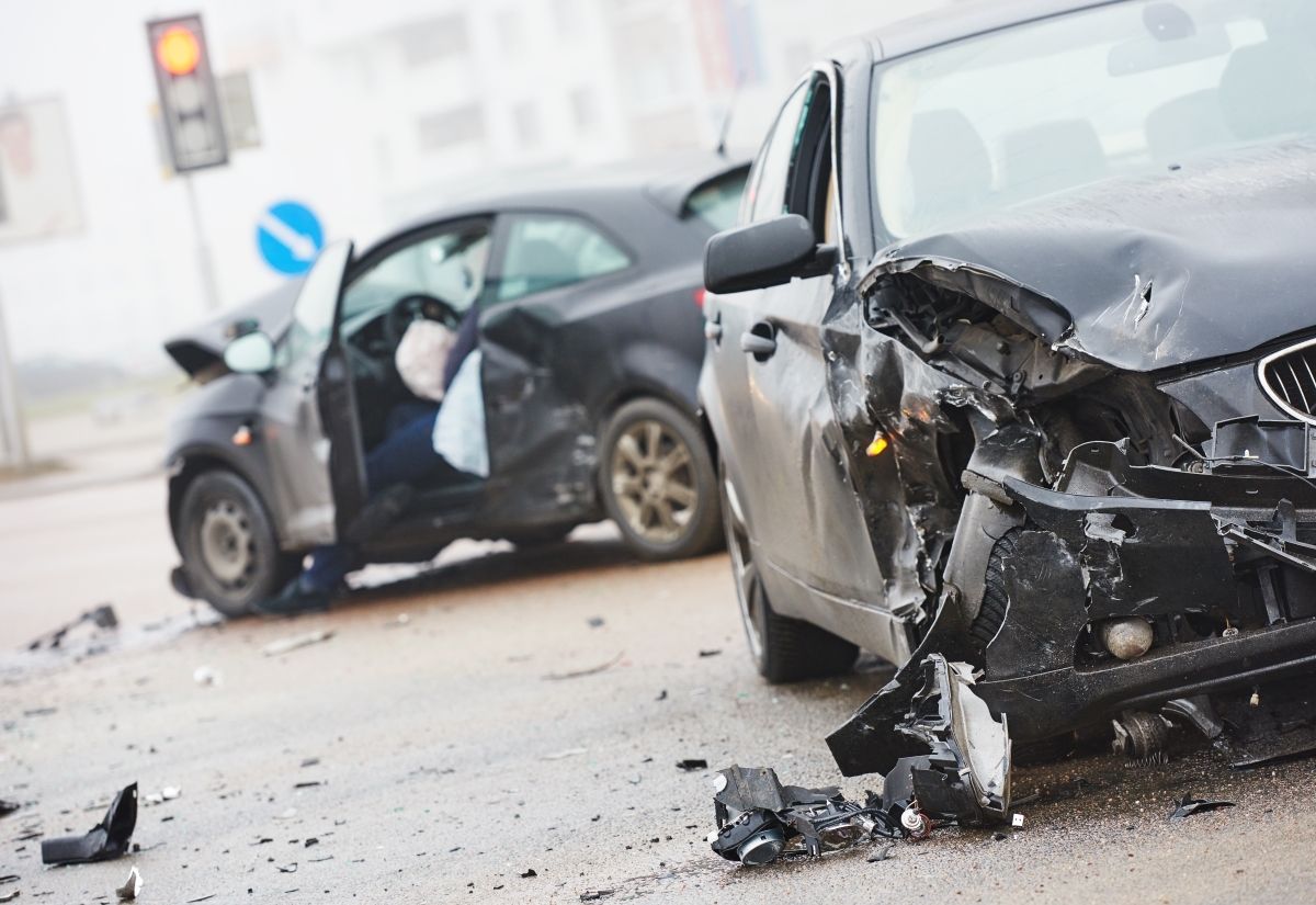 Two cars collided on a city street, showing visible damage and debris scattered across the roadway after the accident
