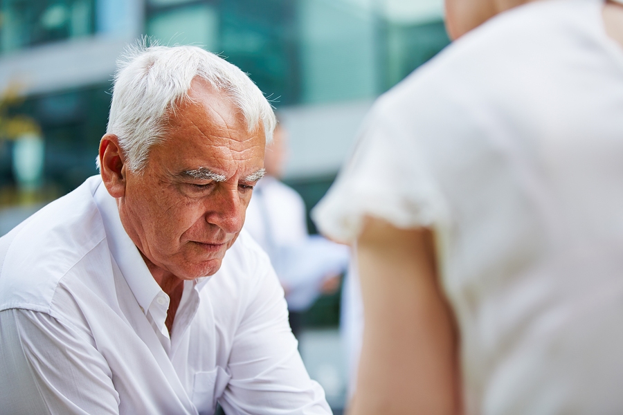Pensive elderly businessman sitting thoughtfully, reflecting on work or financial decisions