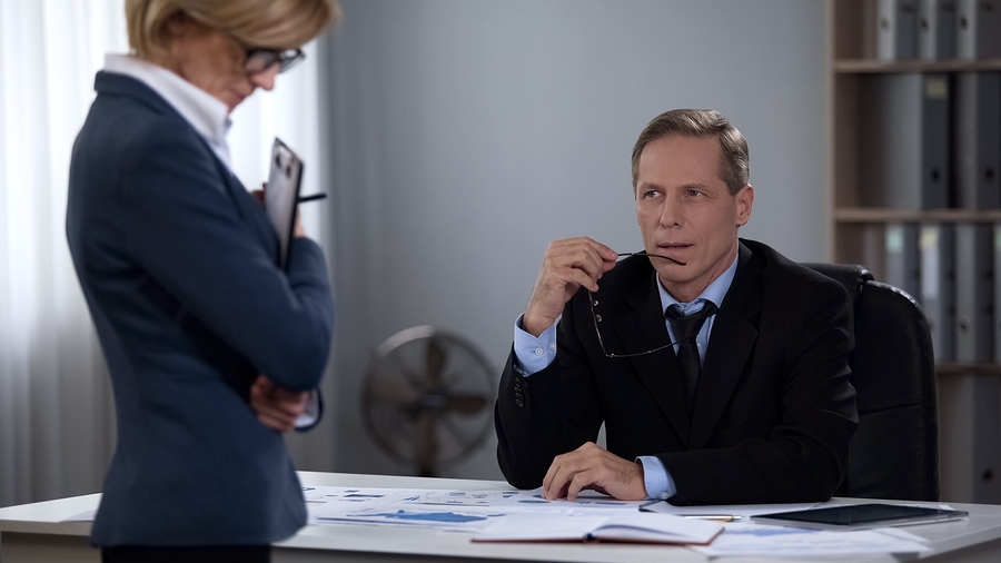 Businesswoman facing workplace discrimination as colleagues criticize and exclude her during a tense office situation