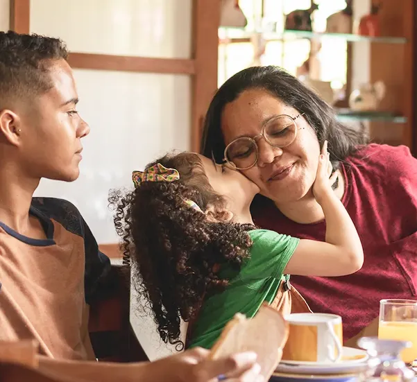Child Kissing Mother on Cheek During Family Breakfast