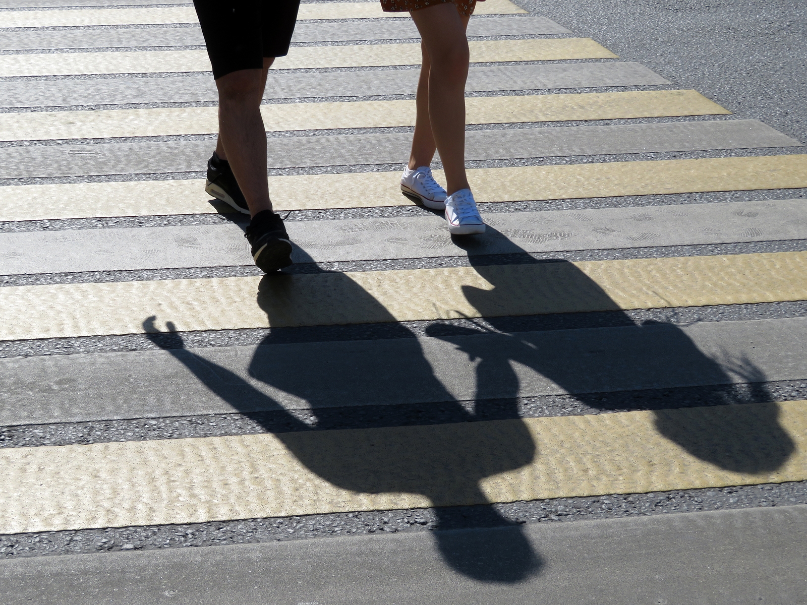 Couple holding hands crossing a street at a pedestrian crosswalk in a busy urban setting
