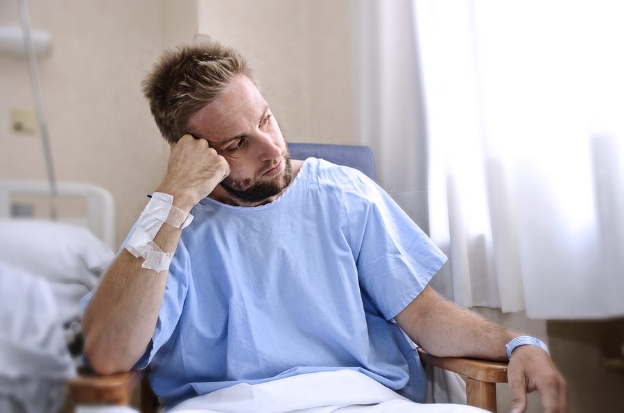Young injured man lying in hospital bed recovering from accident with visible pain and medical treatment equipment