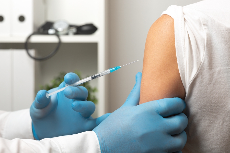 Doctor administering vaccine injection to patient arm in clinical setting