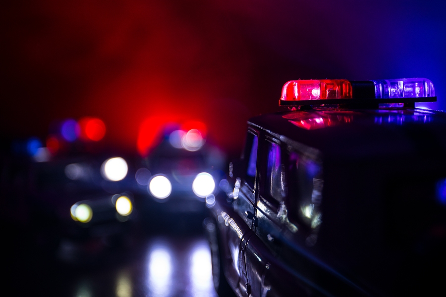 Police car chasing suspect vehicle at night with flashing lights during high-speed emergency pursuit
