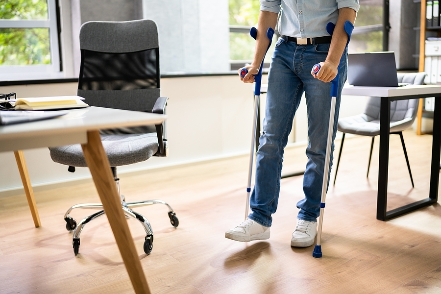 Injured worker using crutches at the workplace, returning to duties after an accident