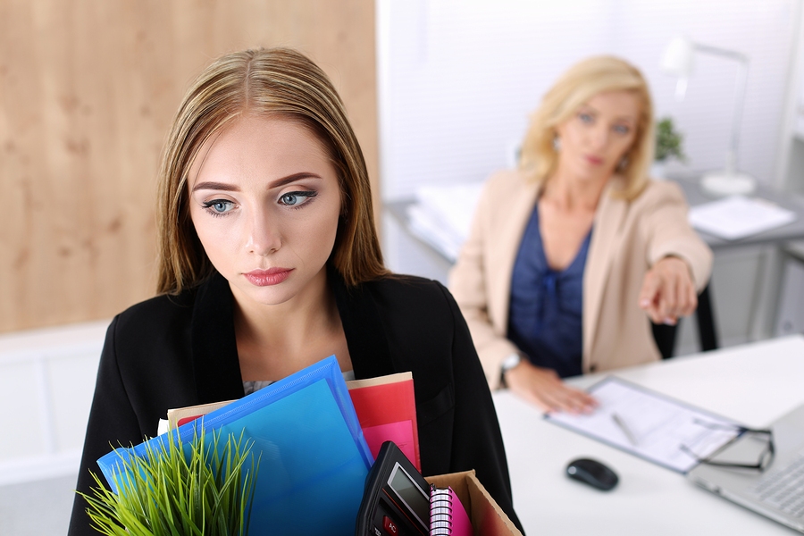 Dismissed office worker carrying a box of personal belongings after being fired and leaving the workplace