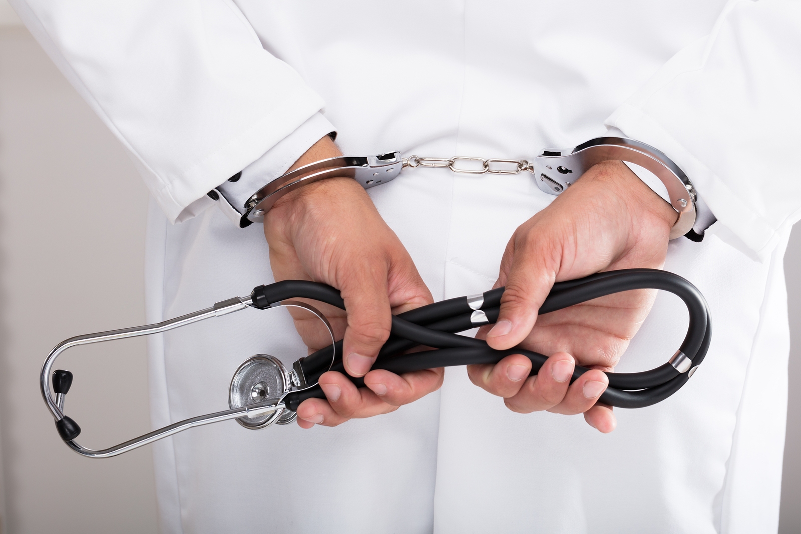 Doctor in handcuffs symbolizing medical malpractice, fraud, or healthcare legal issues