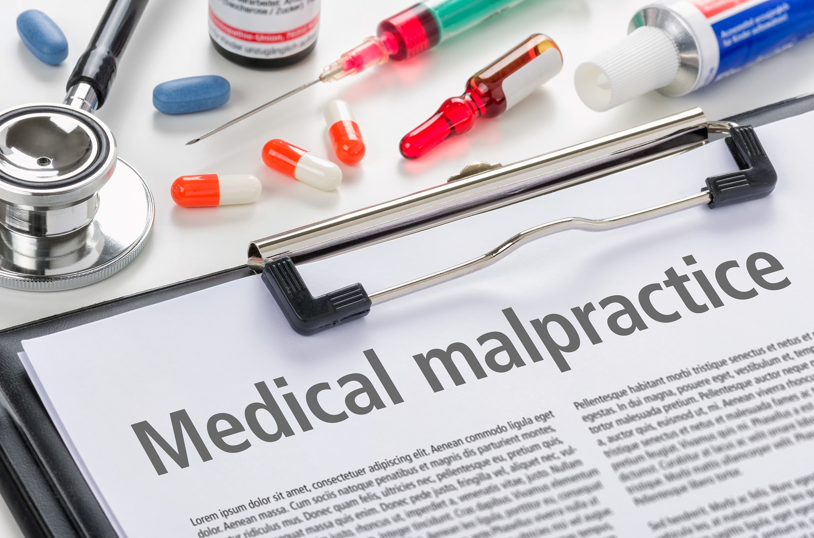 Medical malpractice written on a clipped page with drugs