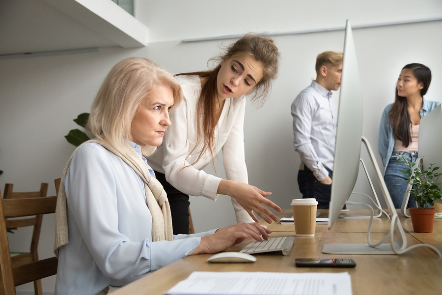 Doctor mentoring employee and correcting work in office teamwork setting