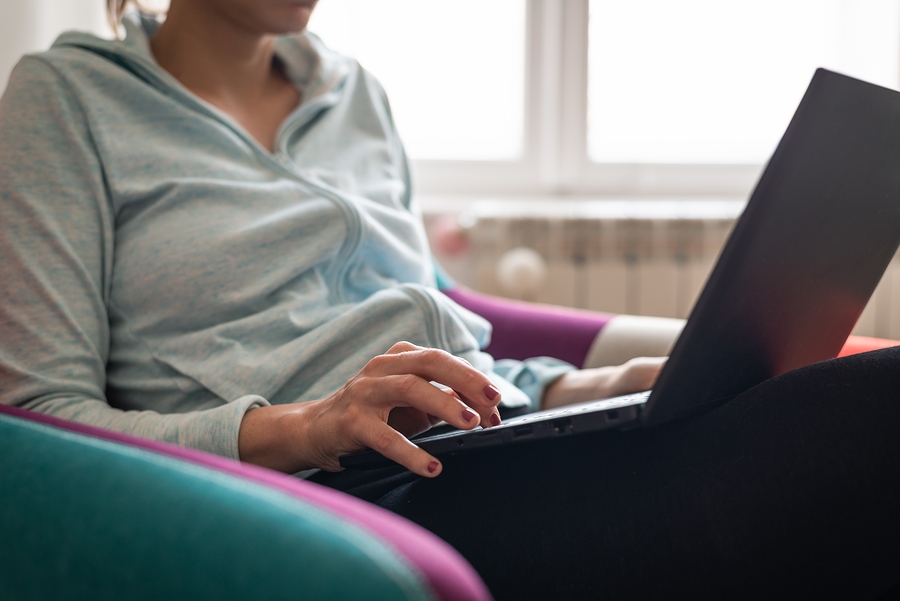 Woman working on a laptop from home, focused on tasks in a comfortable remote workspace