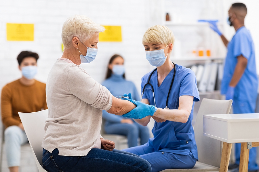 Senior patient receiving COVID-19 vaccine injection from doctor in clinic setting