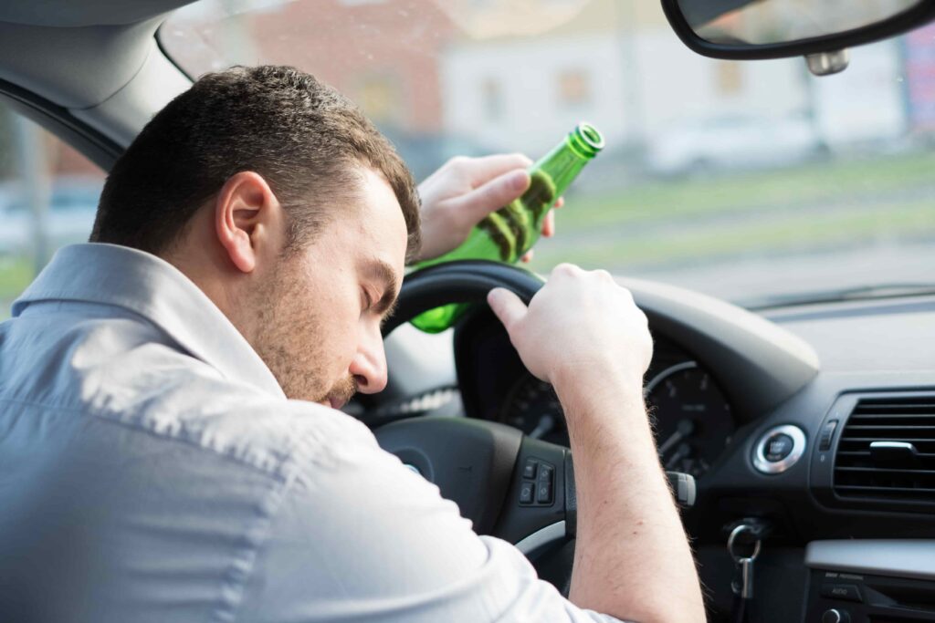 Drunk driver holding alcohol bottle while driving.