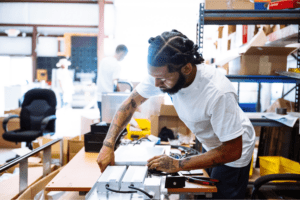 Factory worker assembling equipment at a workbench in an industrial workspace.