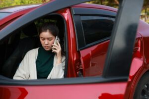 Injured woman sitting in red car after accident speaking on phone about Kansas City personal injury claim
