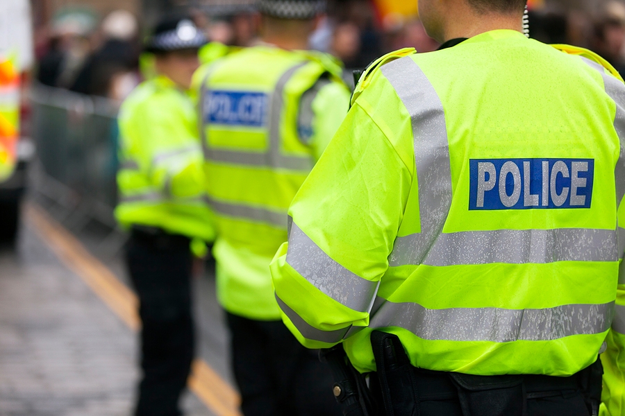 Police officer wearing high-visibility jacket standing on road for traffic control