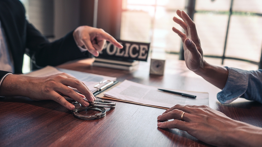Handcuffed suspect being escorted by law enforcement officers during an arrest or investigation