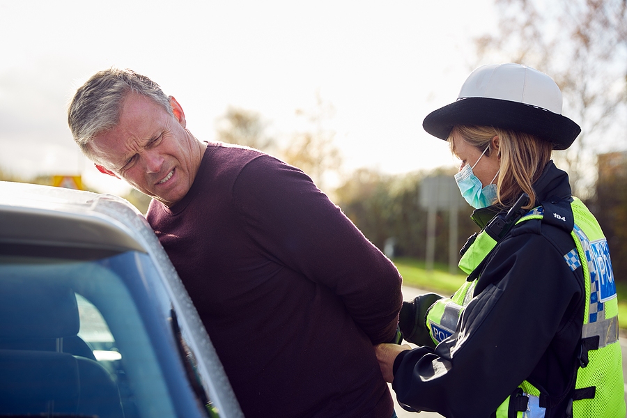 Male driver being handcuffed and arrested by police officer after a traffic violation