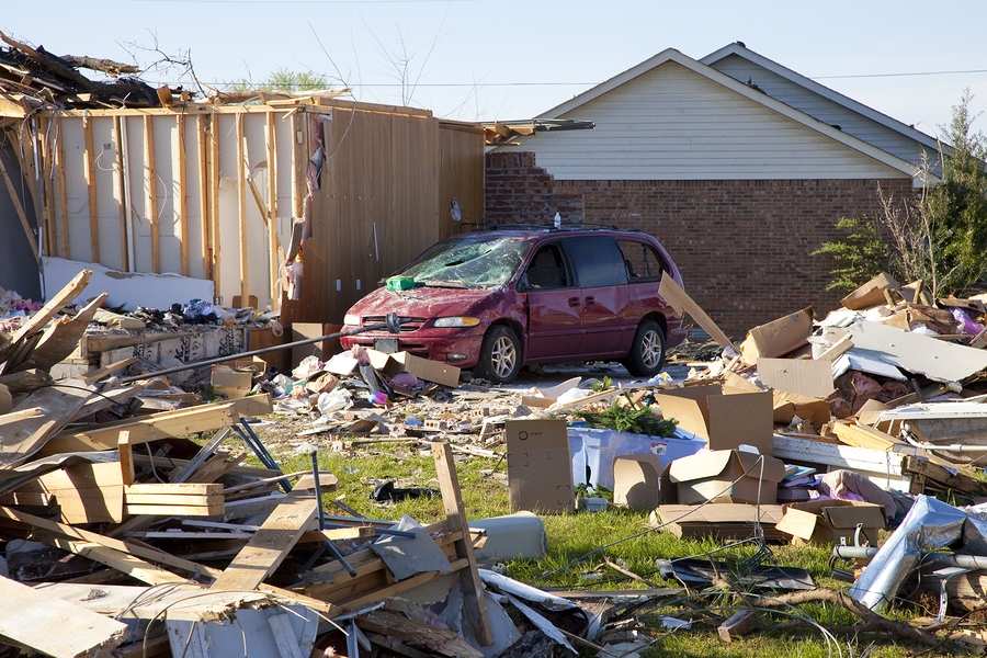 Tornado carving a destructive path through landscape, leaving debris and widespread damage behind