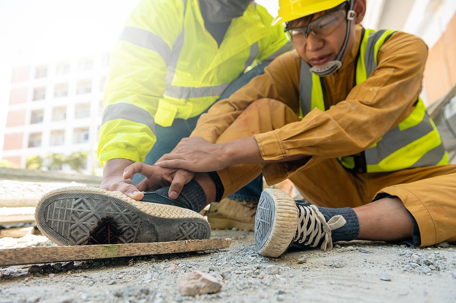 Worker stepping on a hazardous object at a job site, causing a workplace accident and potential injury