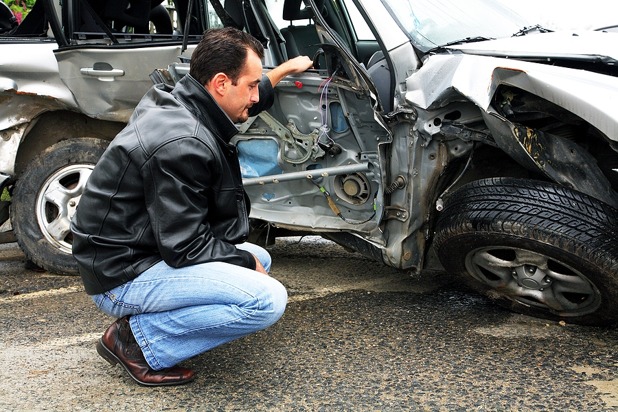 Insurance inspector examining vehicle damage and documenting findings on a clipboard for a claim assessment